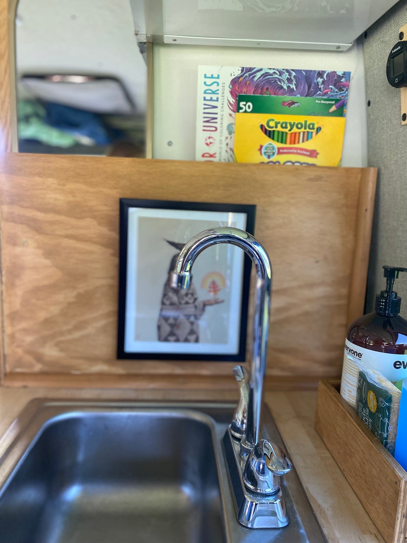 RV rental kitchenette featuring a compact sink, faucet, soap, and creative supplies like Crayola pencils for on-the-road fun.