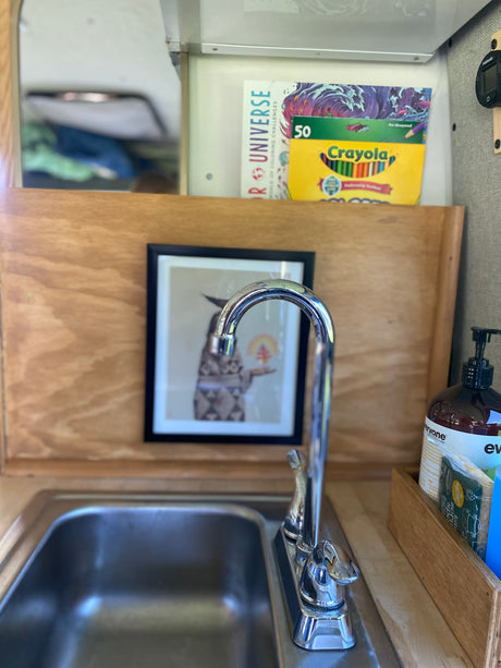 RV rental kitchenette featuring a compact sink, faucet, soap, and creative supplies like Crayola pencils for on-the-road fun.