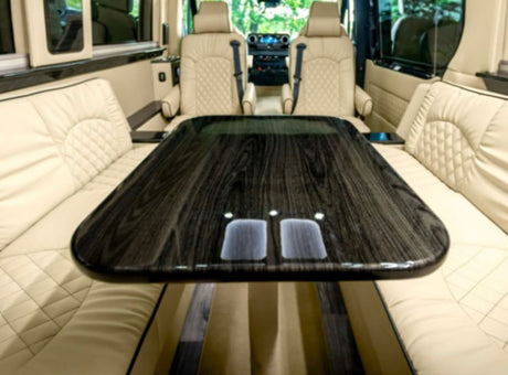 Spacious luxury rv rental interior featuring a large dark wood table and elegant cream quilted leather seating.