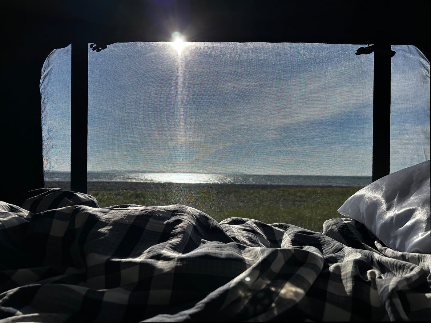  and a bright sun-drenched ocean view through a screened window.|Adventure-ready RV rental van by the ocean at sunset. A custom grey Sprinter camper with open rear doors.|This rugged **rv rental** Winnebago Revel camper van is equipped for adventure — photo 3