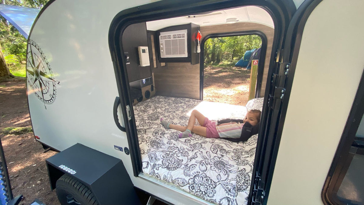 Cozy rv rental interior: child relaxes on the bed at a serene campsite. Ideal for family camping & travel comfort. — photo 14