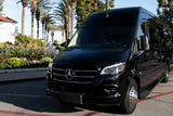 Black Mercedes-Benz Sprinter van, perfect for a luxury RV rental experience, parked by lush gardens and palm trees.