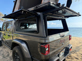 Gray Jeep Gladiator with open camper shell and Roofnest rooftop tent, an ultimate RV rental for beach adventures.