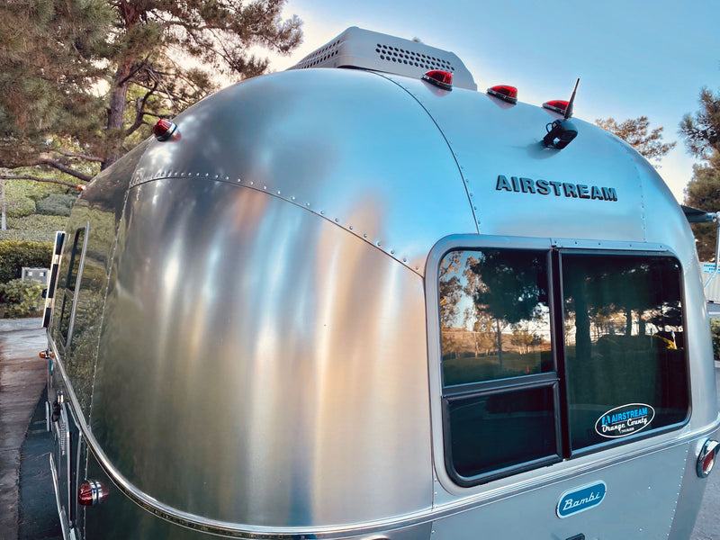  parked among pine trees.|This silver Airstream Bambi travel trailer is perfect for your next rv rental adventure — photo 4