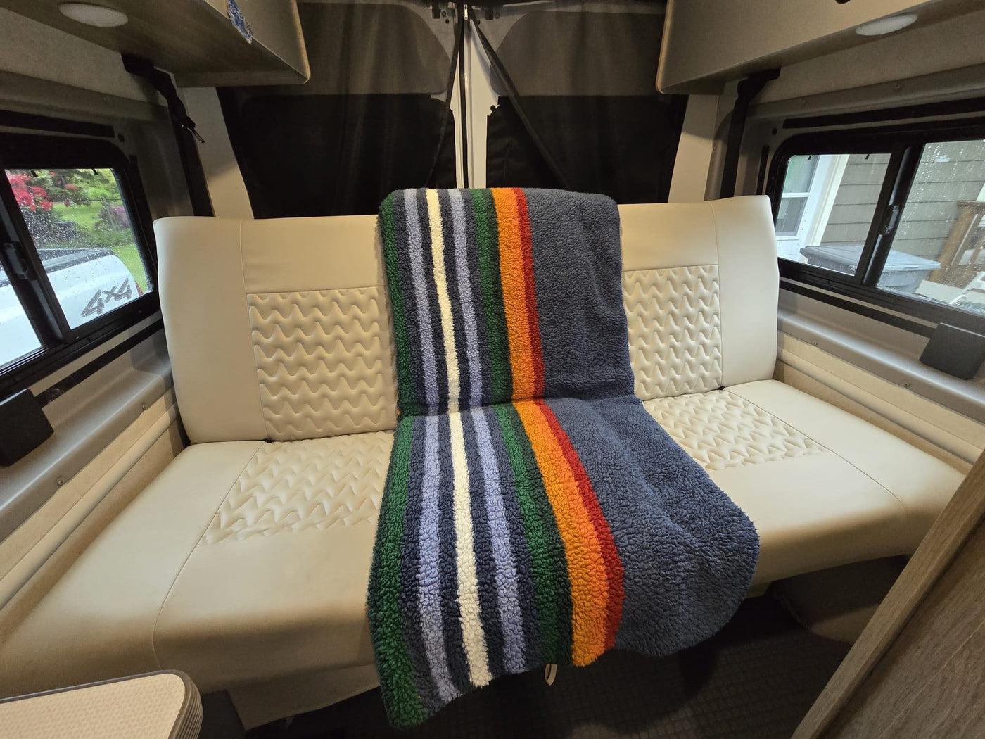 Cozy RV rental interior showing a comfortable bench seat with patterned cushions and a colorful striped blanket. — photo 4