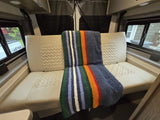 Cozy RV rental interior showing a comfortable bench seat with patterned cushions and a colorful striped blanket.
