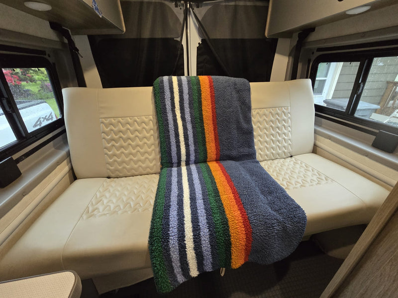 Cozy RV rental interior showing a comfortable bench seat with patterned cushions and a colorful striped blanket. — photo 4