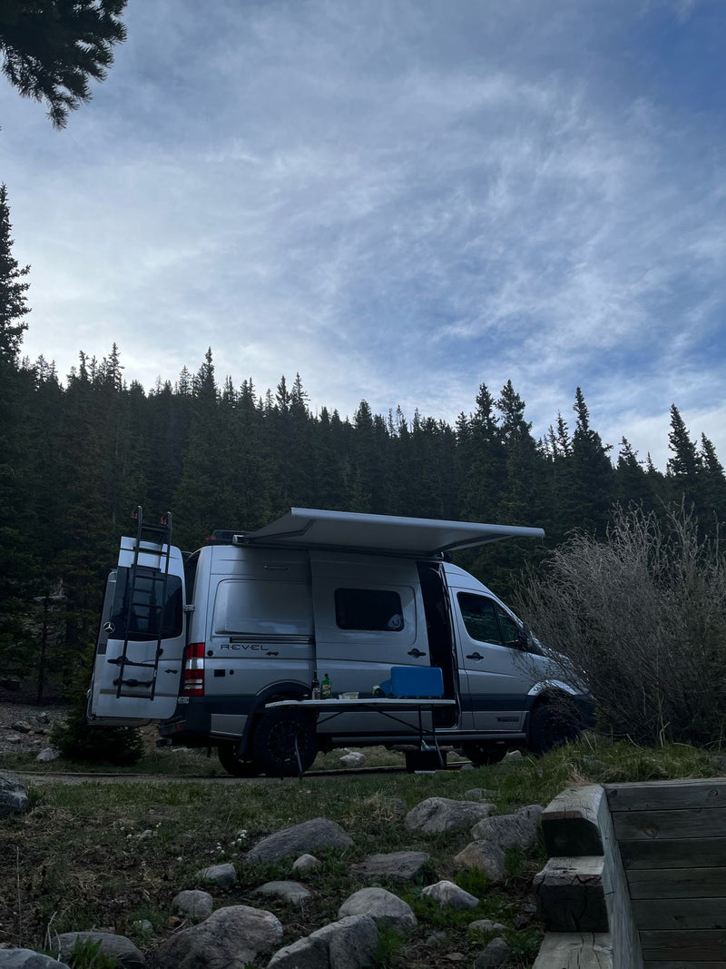  with green forested slopes behind.|Silver Winnebago Revel camper van — photo 2