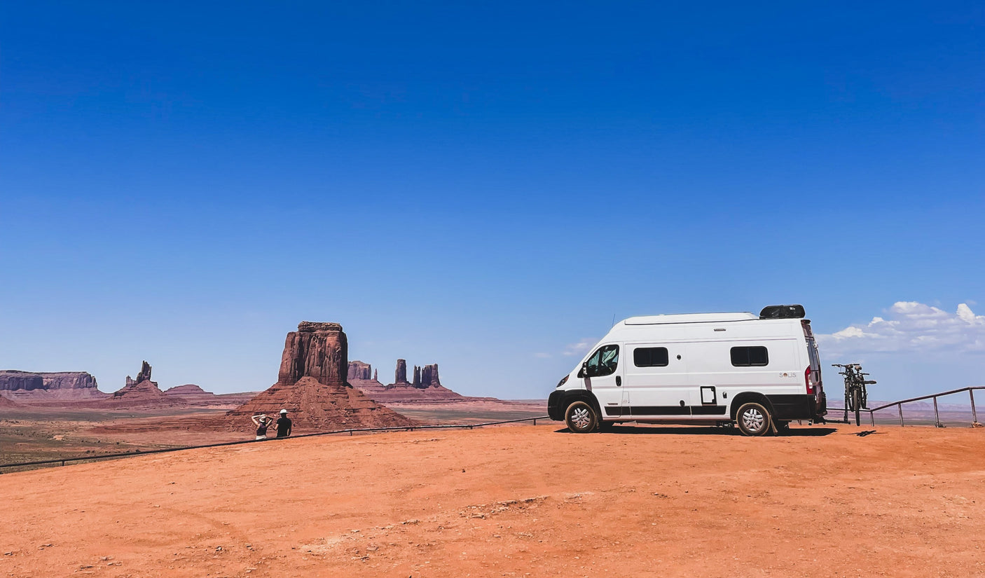 RV rental adventure in iconic Monument Valley, with travelers enjoying the stunning red rock views under a clear sky.