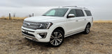 White Ford Expedition SUV, a large and comfortable vehicle in a field. Explore spacious travel options like an rv rental.