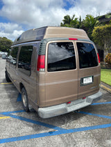 Tan Chevrolet Discovery camper van, likely an RV rental, parked with its distinctive high roof.