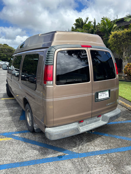Tan Chevrolet Discovery camper van, likely an RV rental, parked with its distinctive high roof.