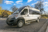 A modern silver Entegra Ethos camper van, perfect for an RV rental adventure, parked on asphalt in a sunny desert landscape.