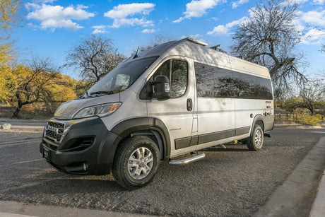 A modern silver Entegra Ethos camper van, perfect for an RV rental adventure, parked on asphalt in a sunny desert landscape.