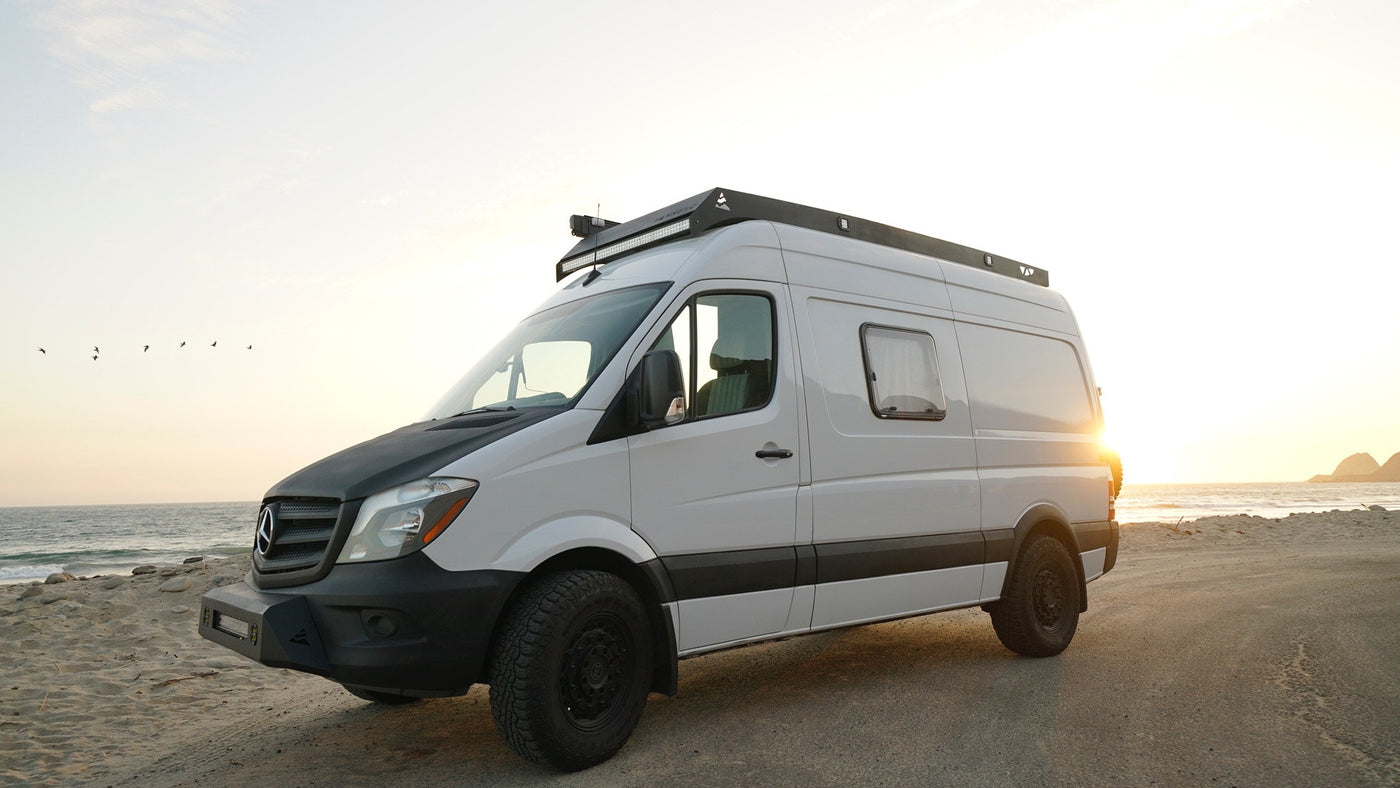 White Mercedes Sprinter camper van parked on a beach at sunset, perfect for an RV rental adventure. — photo 4