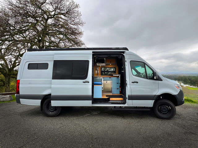Explore in style with this light grey rv rental camper van, showcasing its open side door and modern interior with a kitchen.