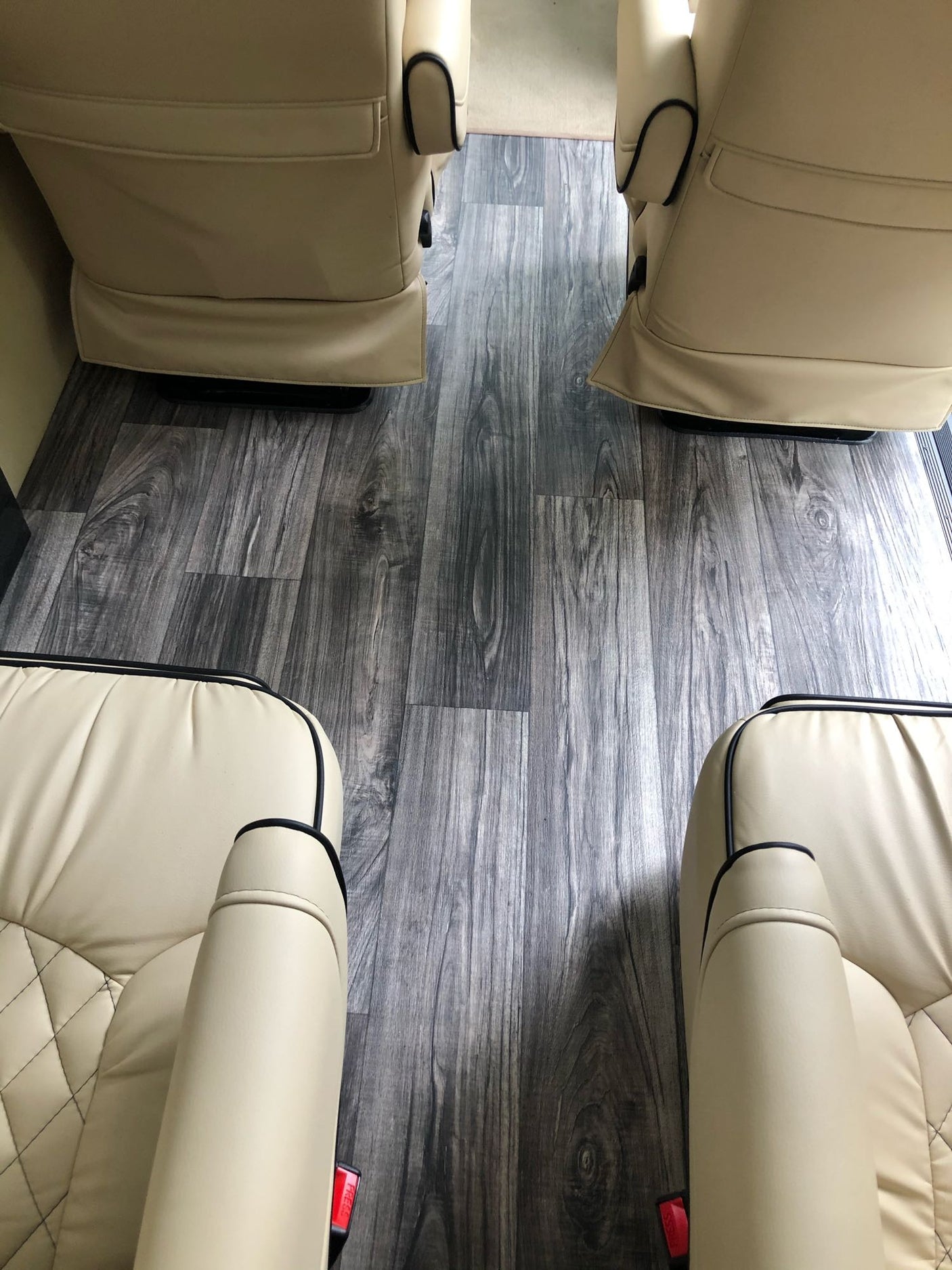 View of plush, beige captain's chairs and sleek wood-look flooring inside an RV rental. Perfect for travel comfort.