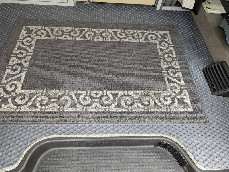 A detailed view of the durable grey flooring and decorative rug in an RV rental, highlighting the textured floor mats. — photo 11