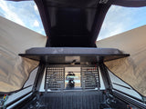 Inside a truck bed camper, showing the mattress and cargo grid. Perfect for your next RV rental adventure!
