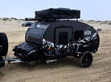 This Beyond Outdoors off-road teardrop camper, ideal for rv rental, features solar panels and rooftop storage, parked on sandy dunes.