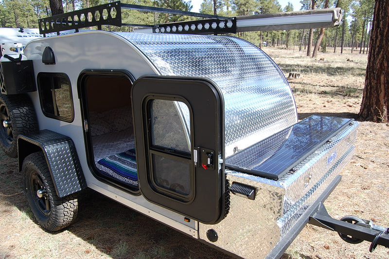 Adventure-ready RV rental: Rugged teardrop camper with open door, bed, solar panel, and off-road tires for camping. — photo 2