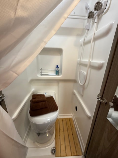 Wanda's wet bath ready for a shower - with shower curtain, towels, biodegradable soap, and a handheld shower head.