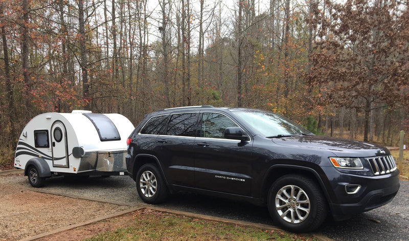  is set up at a wooded campsite with smoke from a fire and another camper.|Enjoying an RV rental getaway!|An RV rental kitchenette features a sink — photo 1