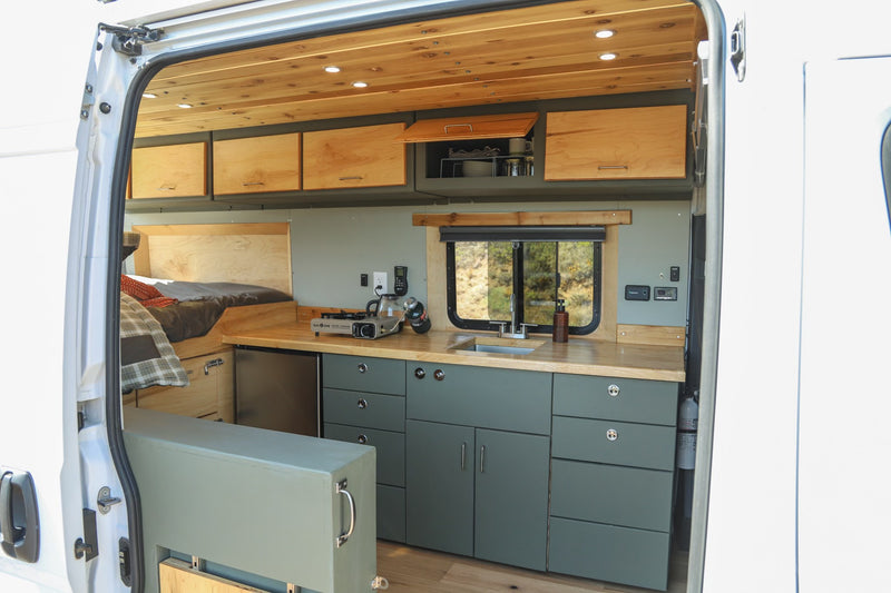  overlooking the iconic Golden Gate Bridge and bay.|White RV rental van overlooking Golden Gate Bridge & San Francisco. Side door open shows camper interior at scenic viewpoint.|Experience van life! This RV rental features a cozy bed — photo 5