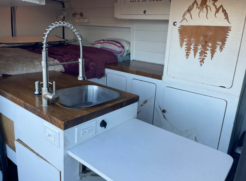  and expansive windshield view.|Compact RV rental interior featuring a cozy bed — photo 7
