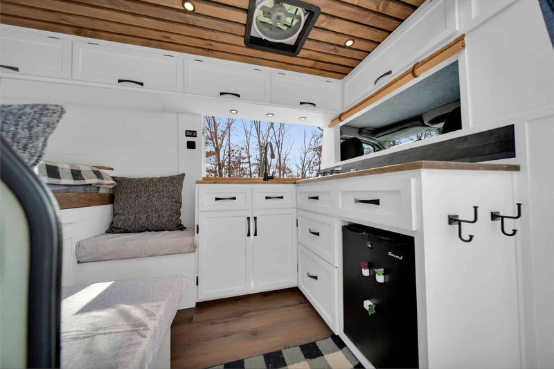 Cozy rv rental interior: white kitchen with sink, fridge, wooden ceiling, and bench seat. — photo 4