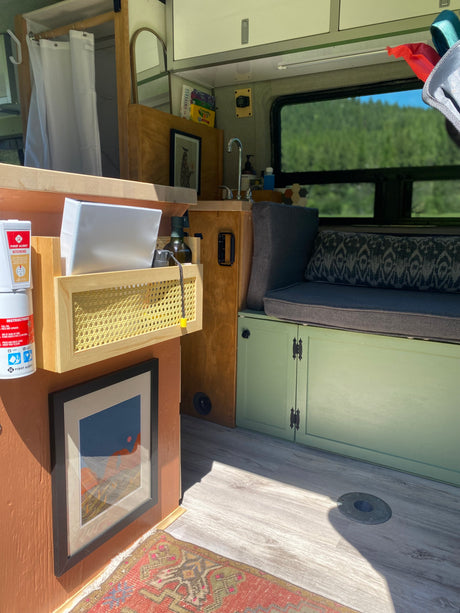 Compact camper van interior, featuring a mini kitchen, comfy bench, and organized storage for an RV rental adventure.