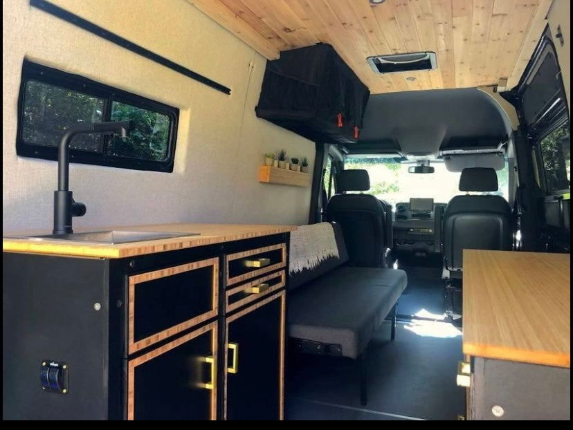 Sleek, custom camper van interior featuring a kitchen, seating, and cozy living space. Ideal for an rv rental.