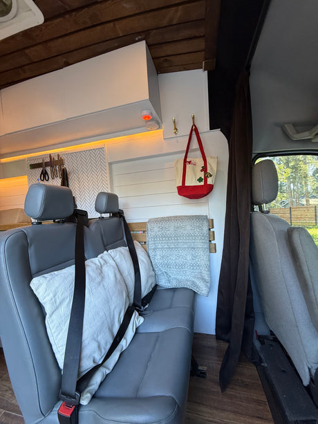 RV rental interior: cozy seating, wooden ceiling, kitchen area with knife rack, and custom storage for comfortable travels.