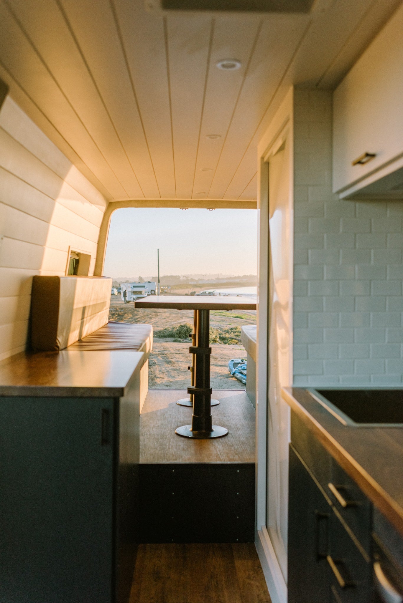 Experience stunning views from your RV rental! Cozy van interior with kitchen & dining, looking out to ocean. — photo 33