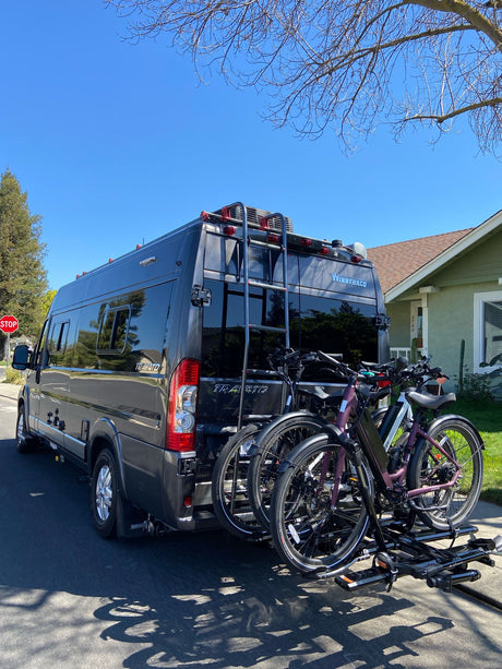 Stylish gray RV rental camper van with a rear bike rack holding two electric bikes, ready for an outdoor getaway.