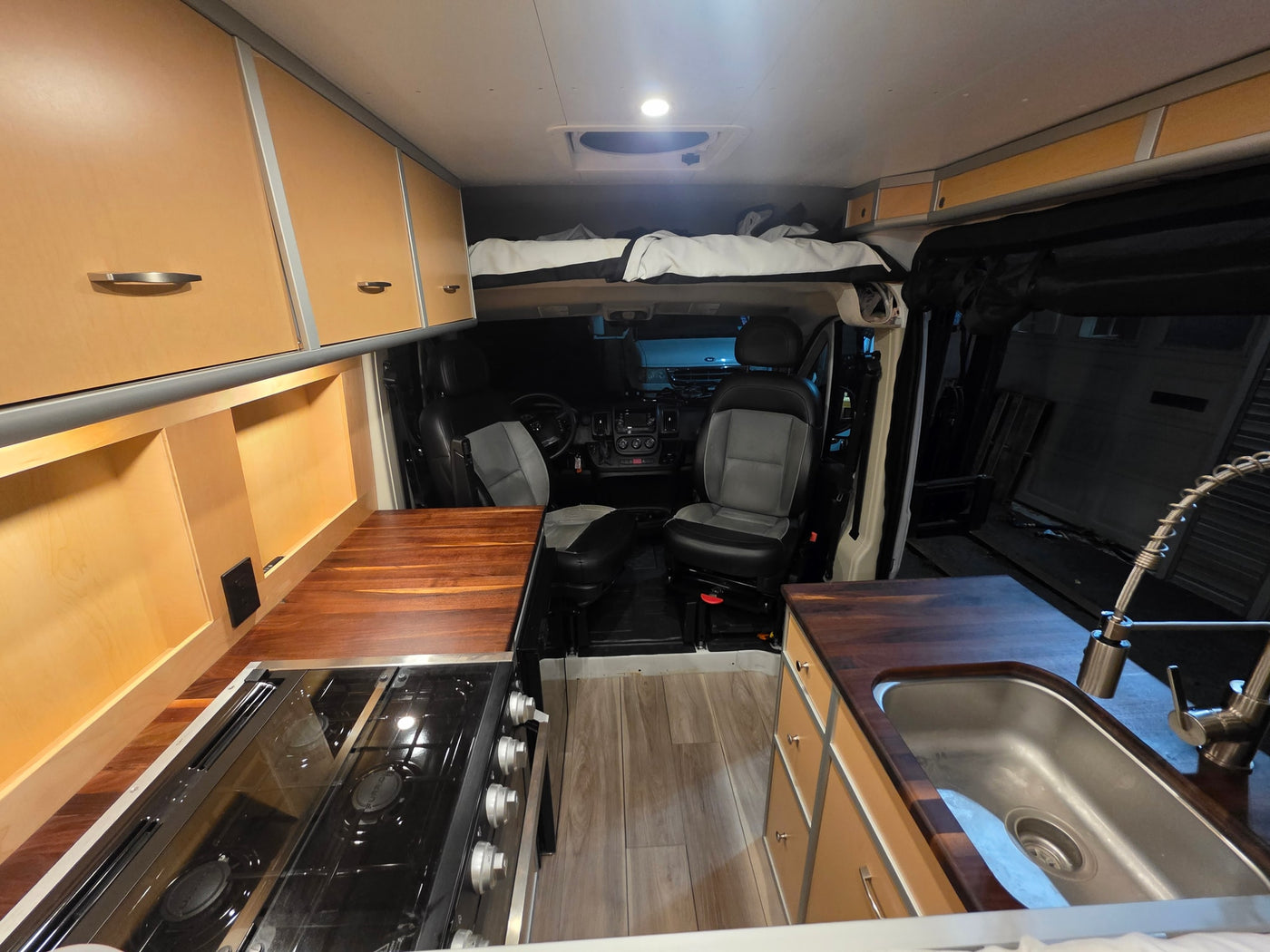 Spacious RV rental interior with a cozy bed, full kitchen, and modern wood cabinetry, perfect for your next adventure. — photo 8