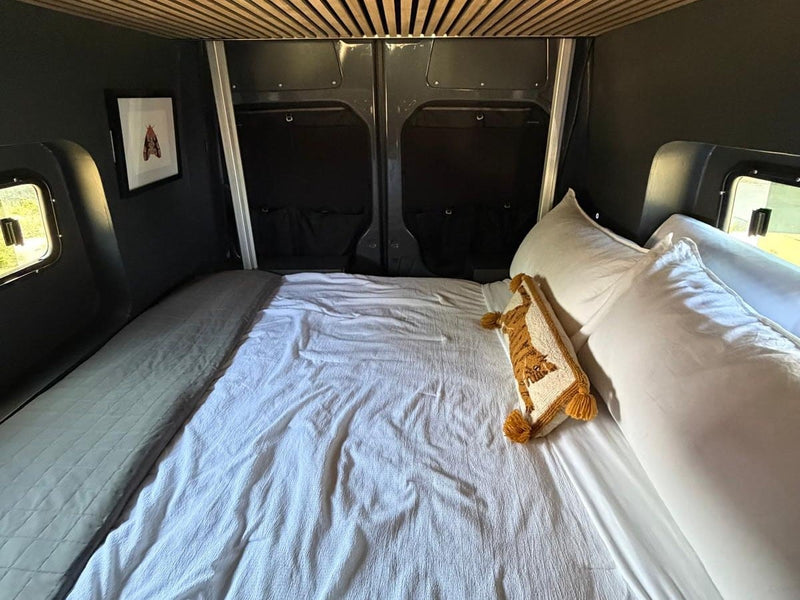  parked on dirt next to houses on a sunny day.|Inviting RV rental bedroom with a large bed — photo 2