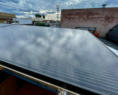Rooftop solar panels on an RV rental, with an industrial backdrop under cloudy skies.