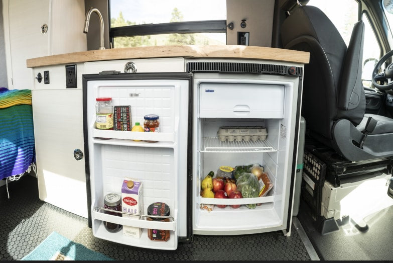 Inside this RV rental, a compact, well-stocked refrigerator and kitchenette are ready for travel.