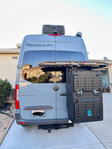 Back of a custom grey Mercedes Sprinter RV rental, with a roof AC, rear cargo box, and bike rack for adventure.