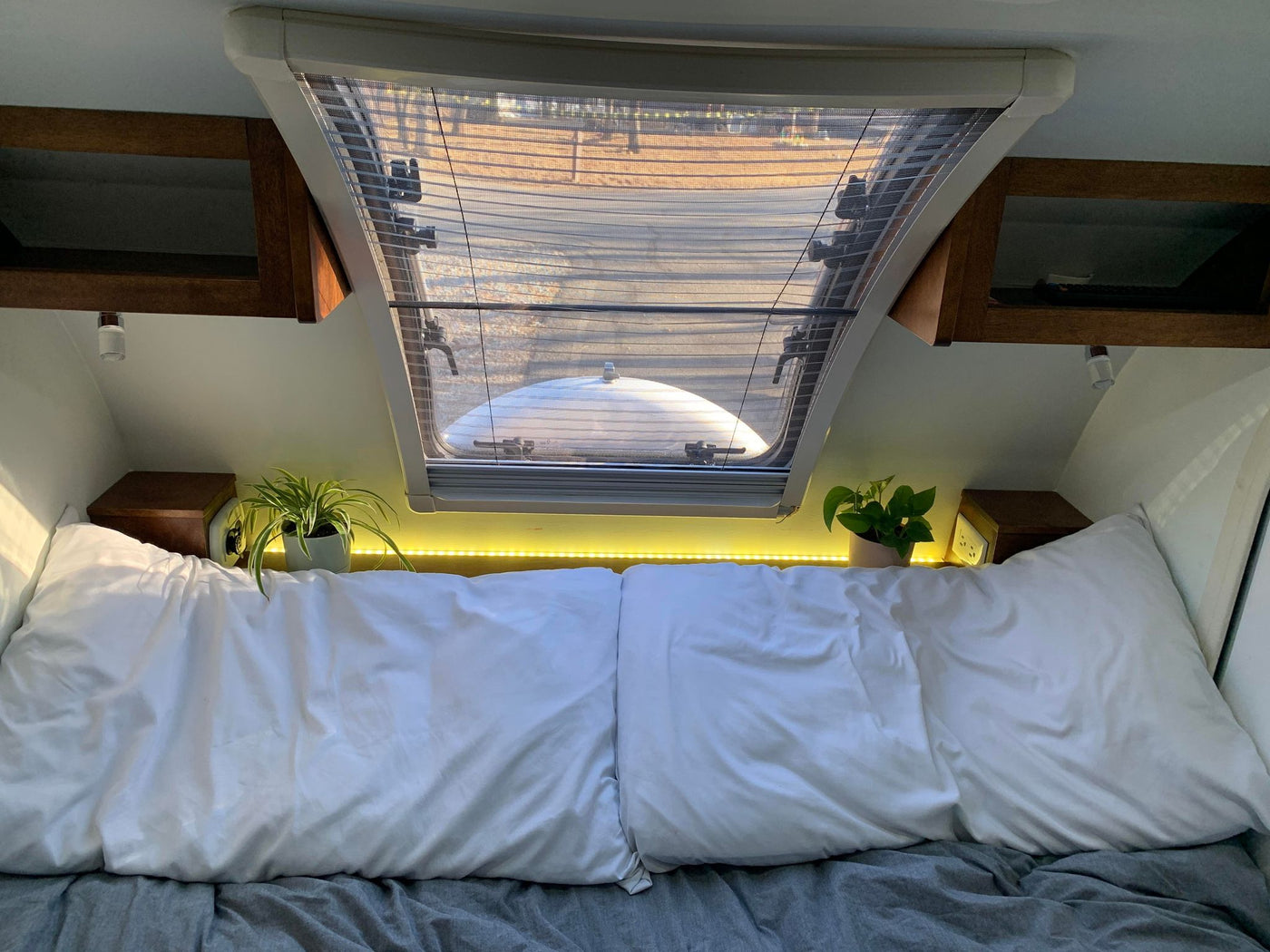  and a window with a tree view.|Experience a compact RV rental interior with a large bed — photo 9