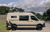 Adventure awaits with this tan Truevan 4x4 camper van. Equipped with off-road tires and roof rack, it's an ideal rv rental.