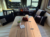 Cozy rv rental interior featuring a foldable wooden table, black & white pillows, and festive Thanksgiving decor like a turkey pillow.