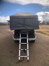 This RV rental features a deployed rooftop tent and ladder on a truck, perfect for outdoor adventure.