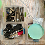 RV rental kitchen essentials: Organized bins with cooking tools, utensils, and plates.