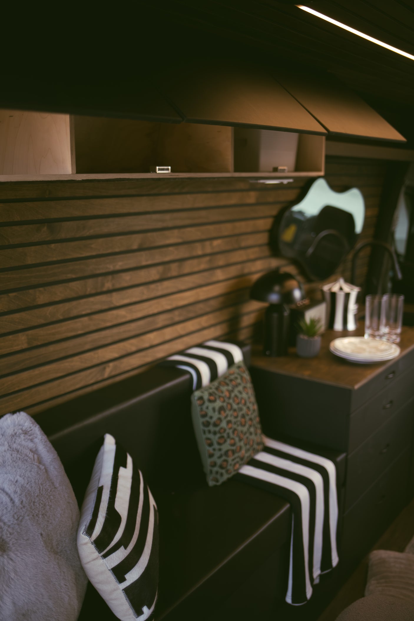Cozy RV rental interior with a bench, stylish pillows, wood-slatted walls, and a convenient coffee station.