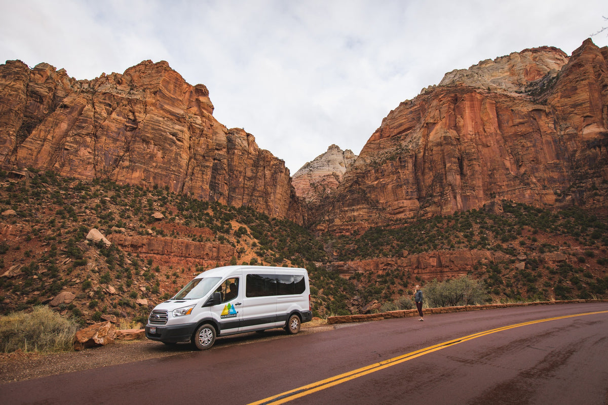 Wandervans rv rental parked in Zion National Park, surrounded by towering red rock mountains and a person admiring the view. — photo 8