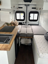 Inside this RV rental, a compact camper van interior featuring a kitchen, flexible bed/seating, and clever storage.