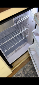 Empty Isotherm refrigerator in an RV rental. View shows clean wire shelves and door compartments, ready for your trip.