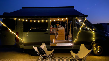 Cozy RV rental setup at dusk: illuminated camper van with string lights, open door, and outdoor chairs, perfect for van life.